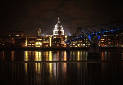 Illuminated st paul cathedral in front of thames river at night