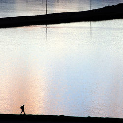 High angle view of silhouette person standing by sea
