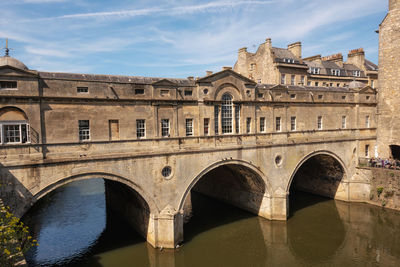 Arch bridge over river against buildings