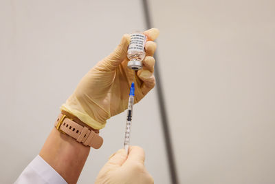 Cropped hand of doctor holding vial and injection at hospital