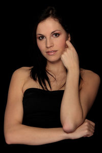 Portrait of a smiling young woman over black background