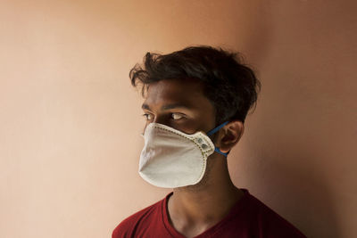 Young man with mask against wall