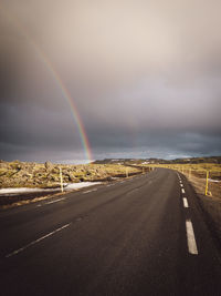 Rainbow over road against sky