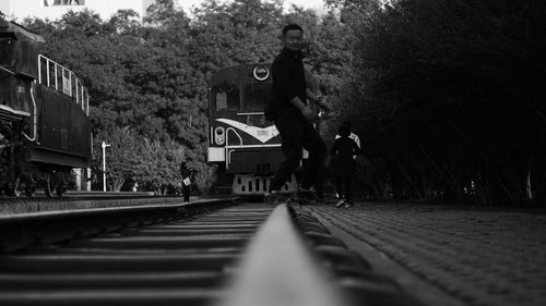 Young man crossing railroad track against train