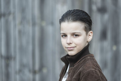 Portrait of young woman standing against wall