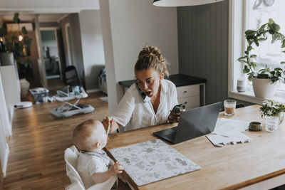 Multitasking mother taking care of baby and working from home