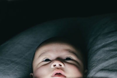 Close-up of cute baby boy lying on bed at home