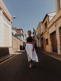 Portrait of young woman standing on building against clear sky