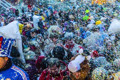 Crowd throwing colorful confetti in city during celebration