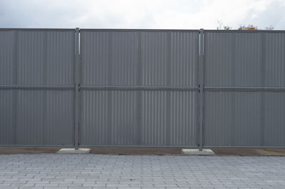 Footpath by wall against sky in city