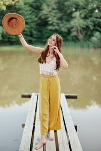 Young woman with arms raised standing against railing