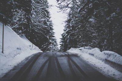 Snow covered road passing through forest