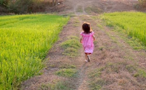 Rear view of girl running on field