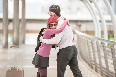 Smiling woman embracing boyfriend on elevated walkway at airport