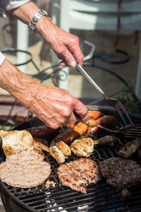 Close-up of man preparing food on barbecue grill