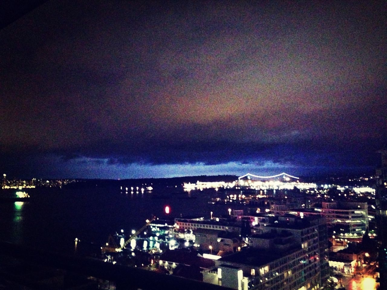 illuminated, building exterior, architecture, night, city, built structure, cityscape, sky, cloud - sky, residential district, residential building, high angle view, dusk, residential structure, cloudy, crowded, city life, storm cloud, outdoors, weather