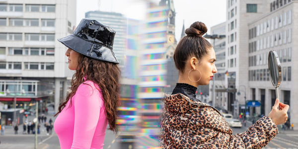 Friends with mirror standing in city