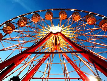 Low angle view of ferris wheel against clear blue sky