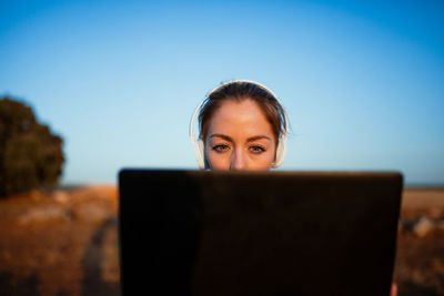 Portrait of woman using smart phone against blue sky