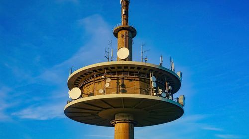 Low angle view of communications tower against blue sky