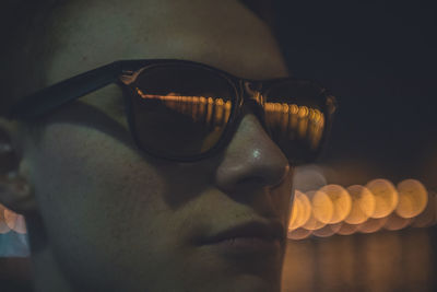 Close-up of man wearing sunglasses at night