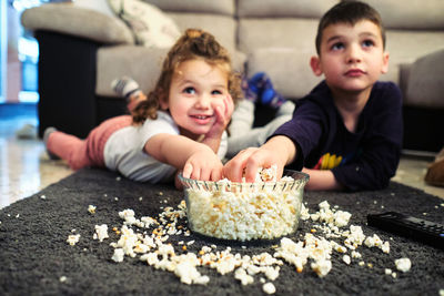 Siblings watching a home movie while eating popcorn