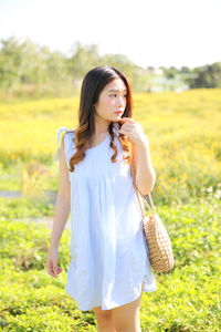 Beautiful young woman looking away while standing on land