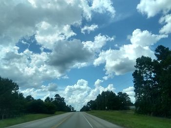 Road amidst trees against sky