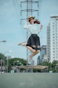 Full length of young woman jumping on road