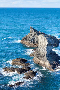 Rock formation in sea against sky