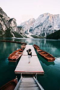 Rear view of woman walking on pier over lake against sky