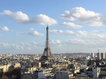 Aerial view of buildings in city against cloudy sky