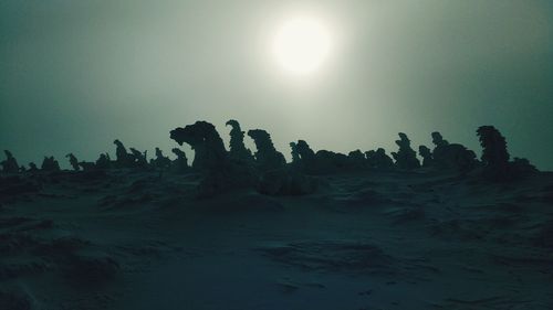 Silhouette rock formations on landscape against sky