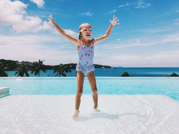 Full length of girl standing in infinity pool