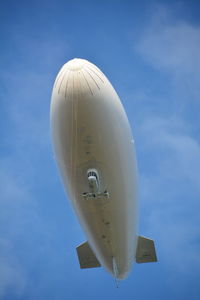 Low angle view of blimp flying against blue sky