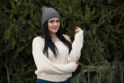 Young woman standing against christmas trees