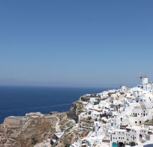 Townscape by sea against clear blue sky