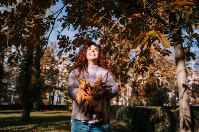 Portrait of smiling young woman standing by tree