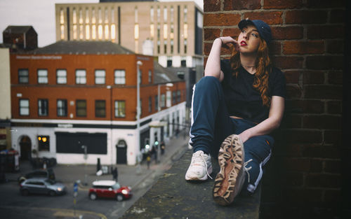 Young woman sitting on retaining wall