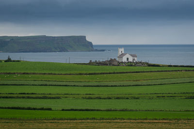 View of fields against calm blue sea