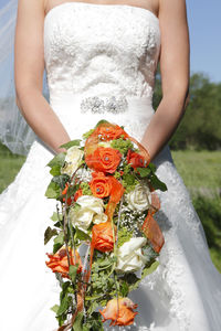 Midsection of bride holding bouquet