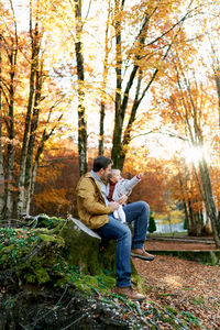 Rear view of woman sitting on field in forest