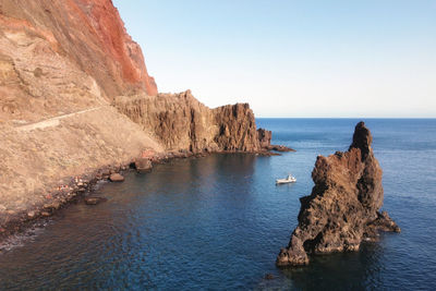 Rock formations by sea against clear sky