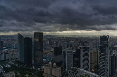 High angle view of buildings in city against storm clouds