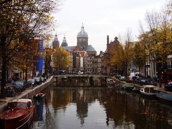 Canal amidst buildings against sky during autumn