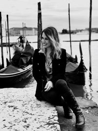 Smiling woman sitting against canal