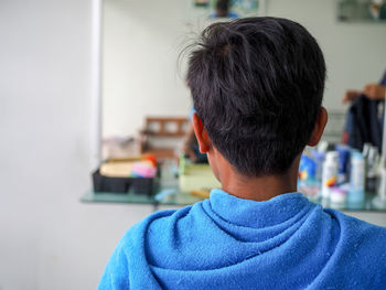 Rear view of man wrapped in blue towel at barber shop