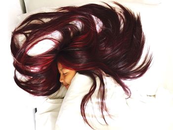 Close-up of woman with dyed red hair in bed