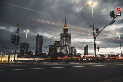 Light trails on road by buildings against sky in city