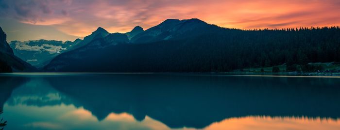 Scenic view of lake and mountains against sky at sunset